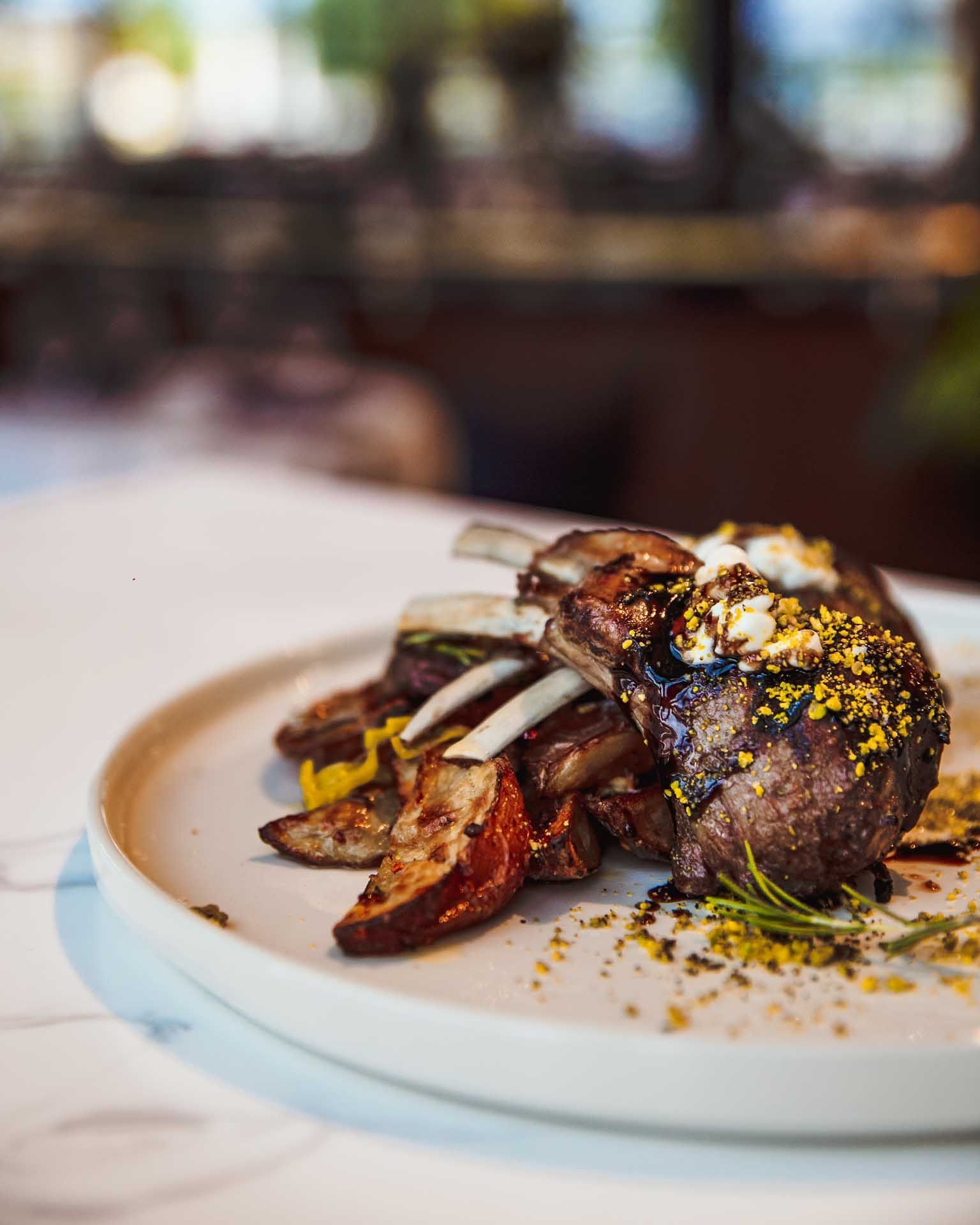a white plate topped with meat and potatoes on a table
