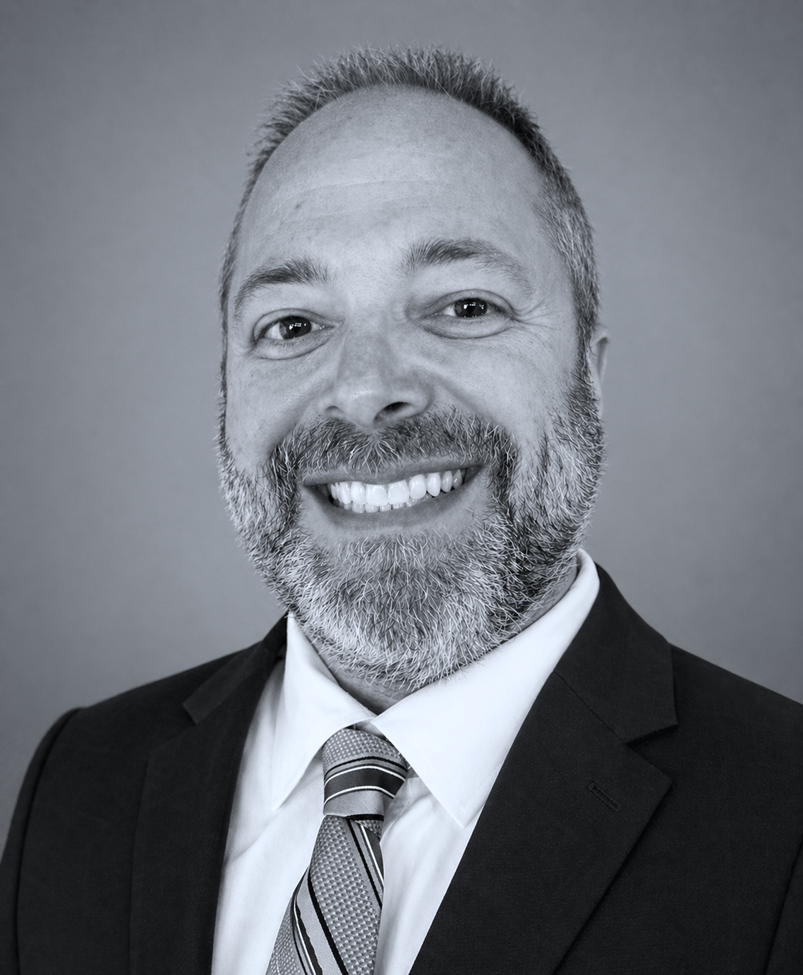 A man in a suit and tie is smiling in a black and white photo.