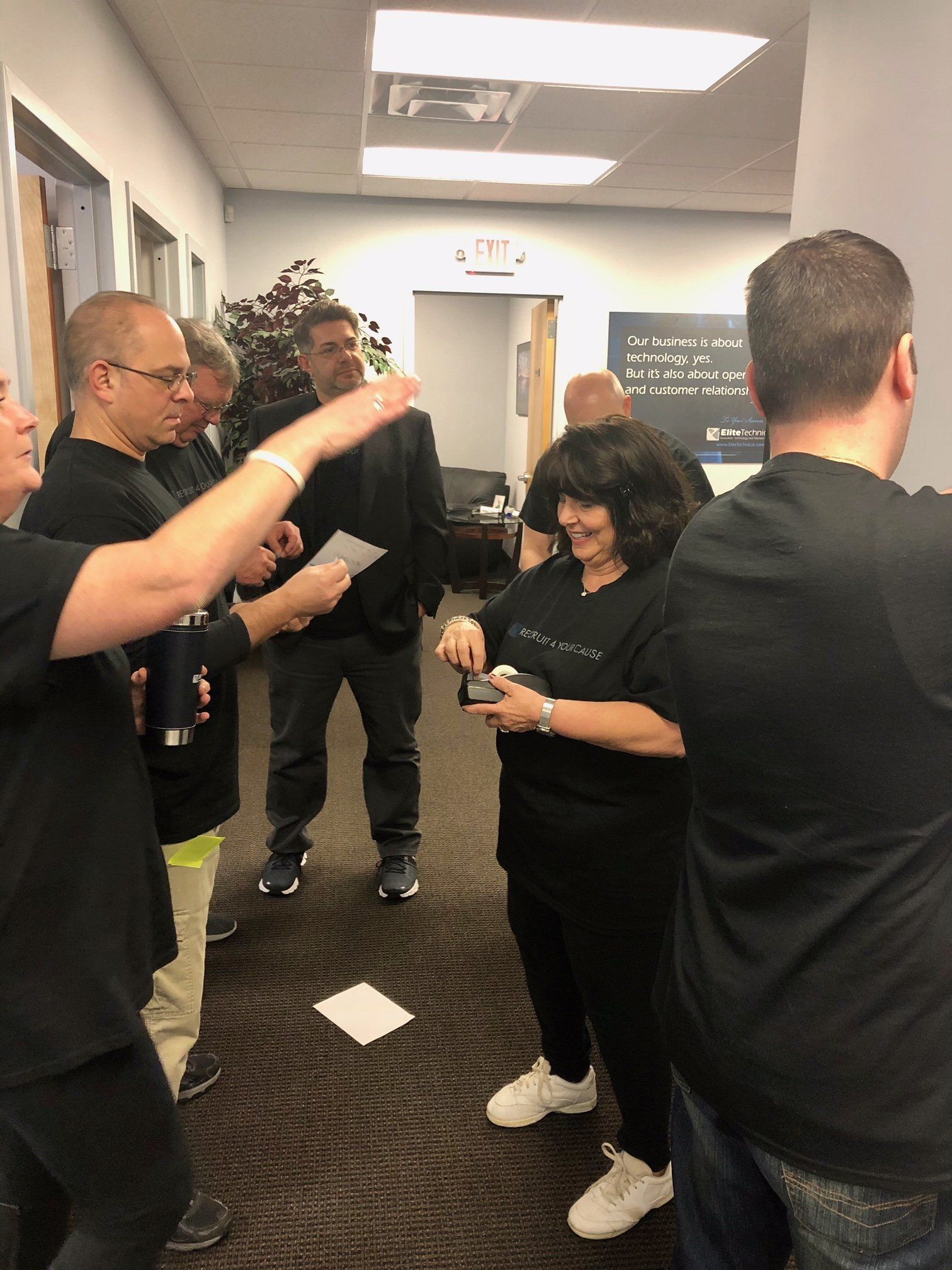 A group of people are standing in a hallway talking to each other.