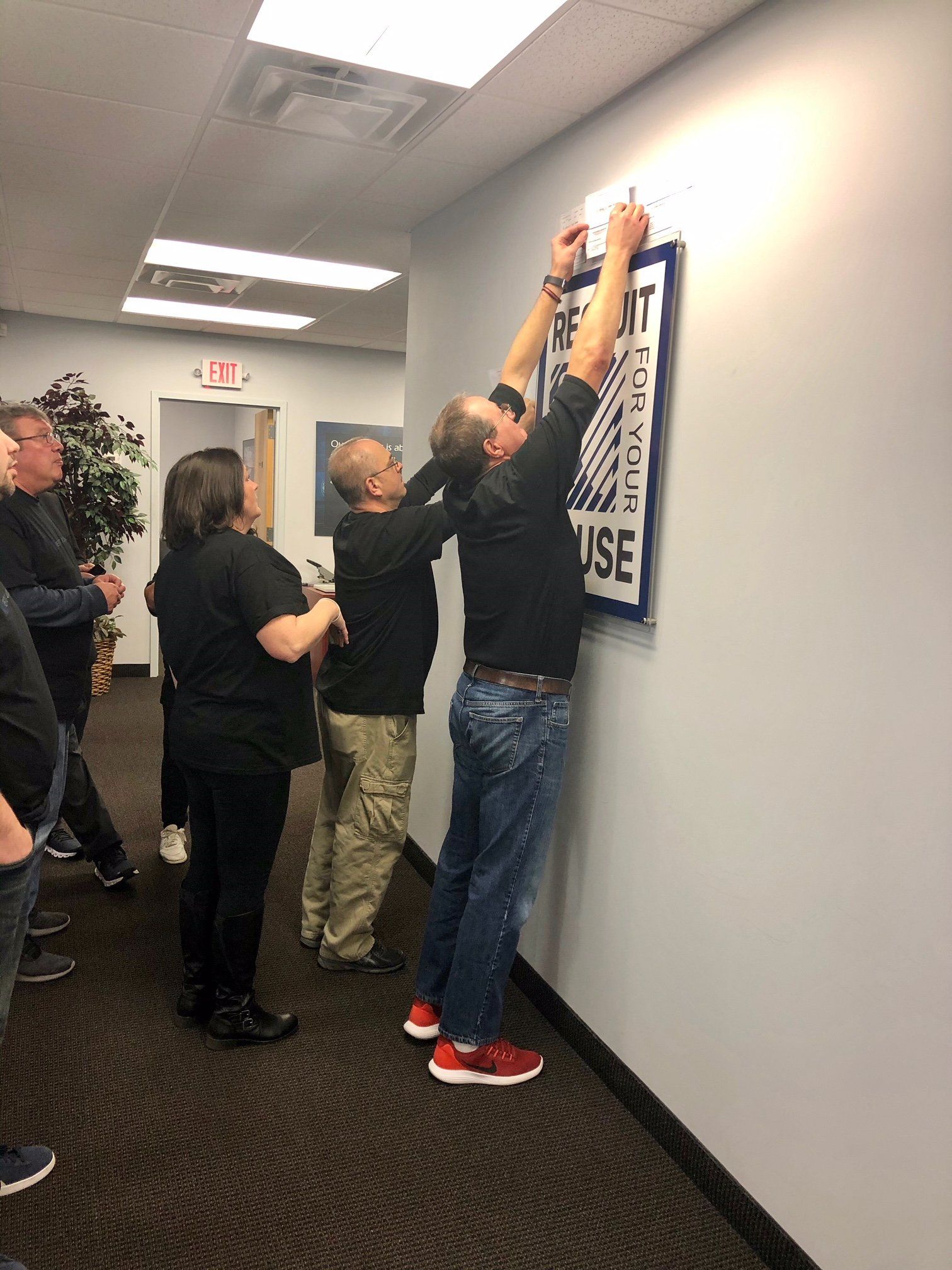 A group of people are hanging a sign on a wall.