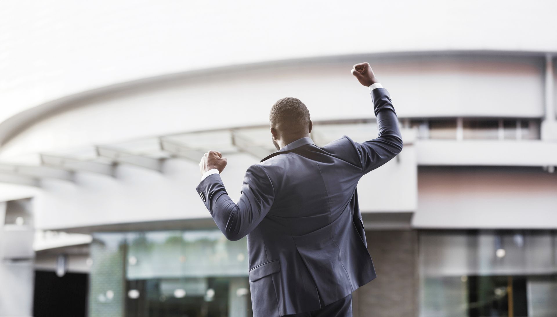 Successful man pumping fist in front of business location