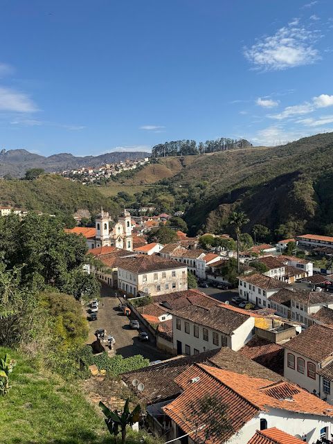 Ouro Preto, Brasil, uma cidade colonial aninhada em colinas verdejantes, com uma igreja visível e telhados de telha vermelha.