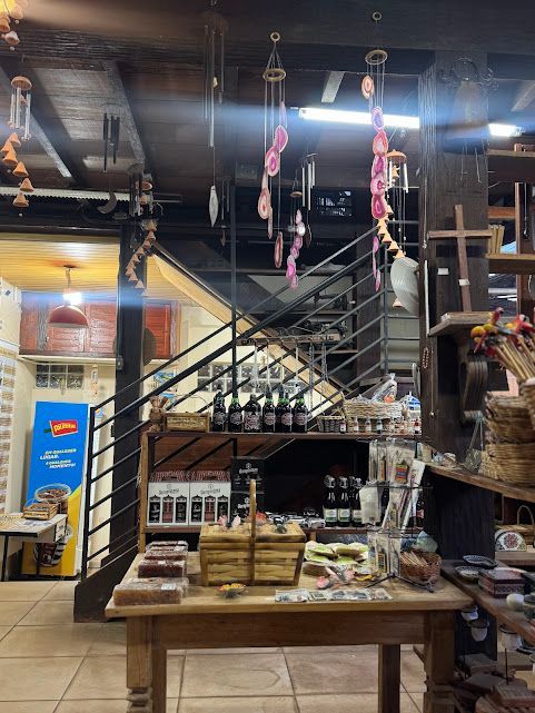 Loja com interior decorado com mesas de madeira, prateleiras, escada e ornamentos pendurados.