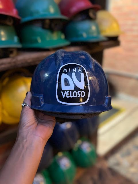 Mão segurando um capacete azul com o logotipo 