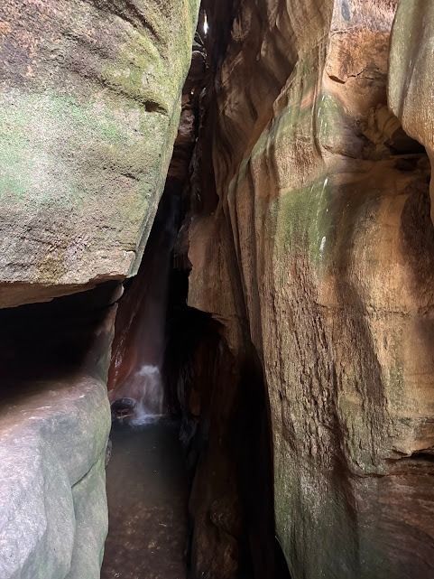 Cânion estreito com paredes rochosas e uma cachoeira ao longe.