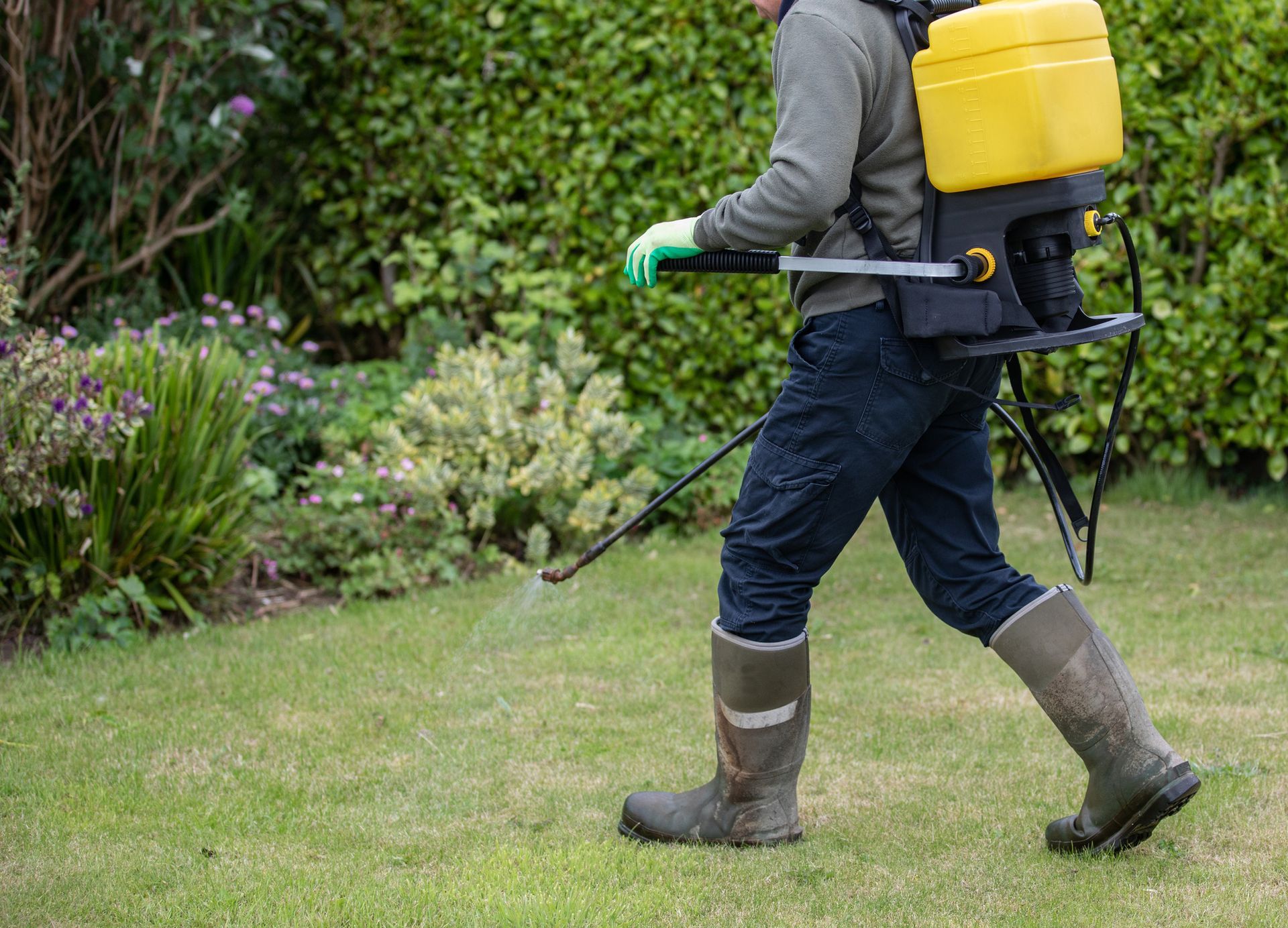 Pest control technician using portable spray rig.
