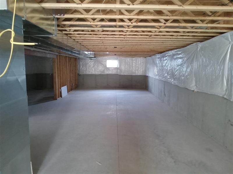 Unfinished crawl space with concrete floor, exposed wooden beams, and plastic wall lining.