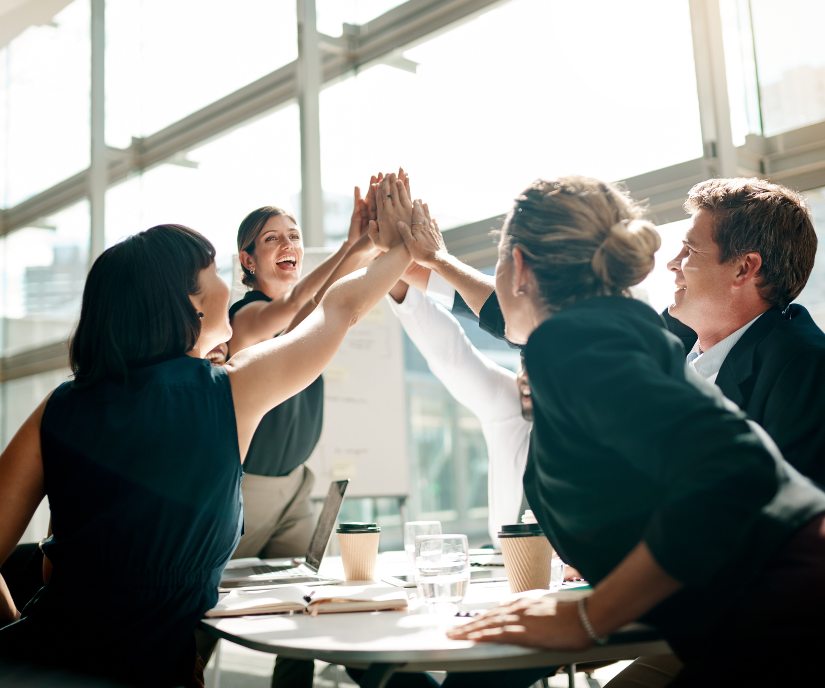 Un grupo de personas se chocan los cinco mientras están sentadas alrededor de una mesa.
