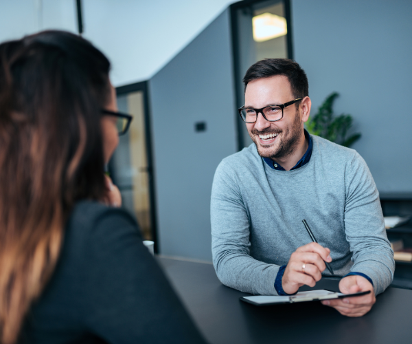 Un hombre y una mujer están sentados en una mesa conversando.