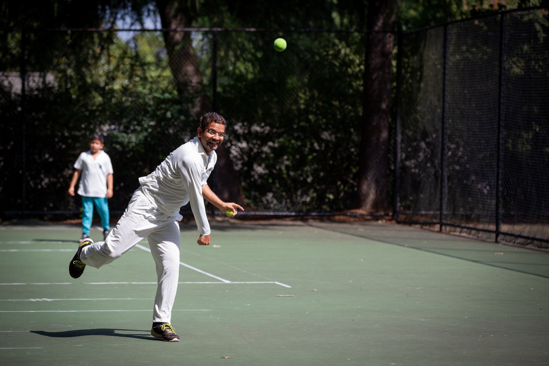 A man is throwing a tennis ball on a tennis court.