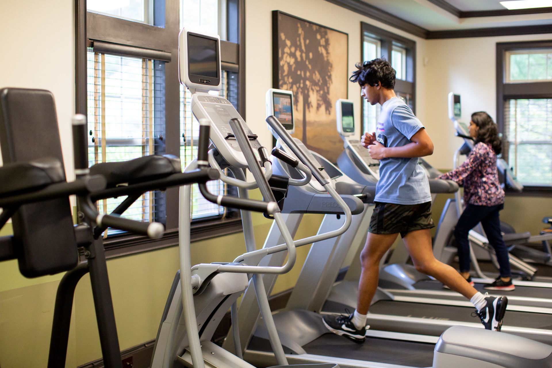 A man and a woman are running on treadmills in a gym.