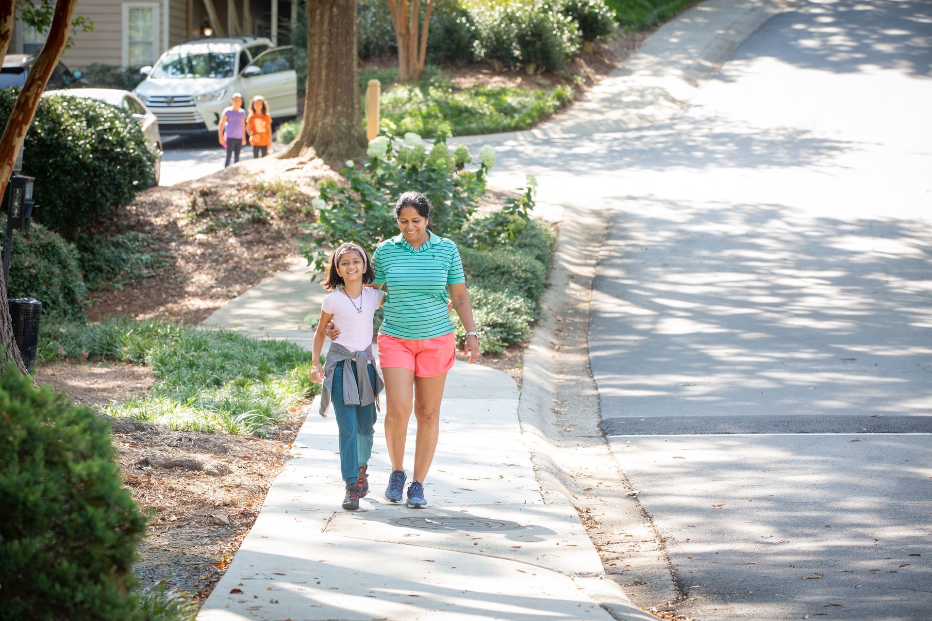 A woman and a girl are walking down a sidewalk.
