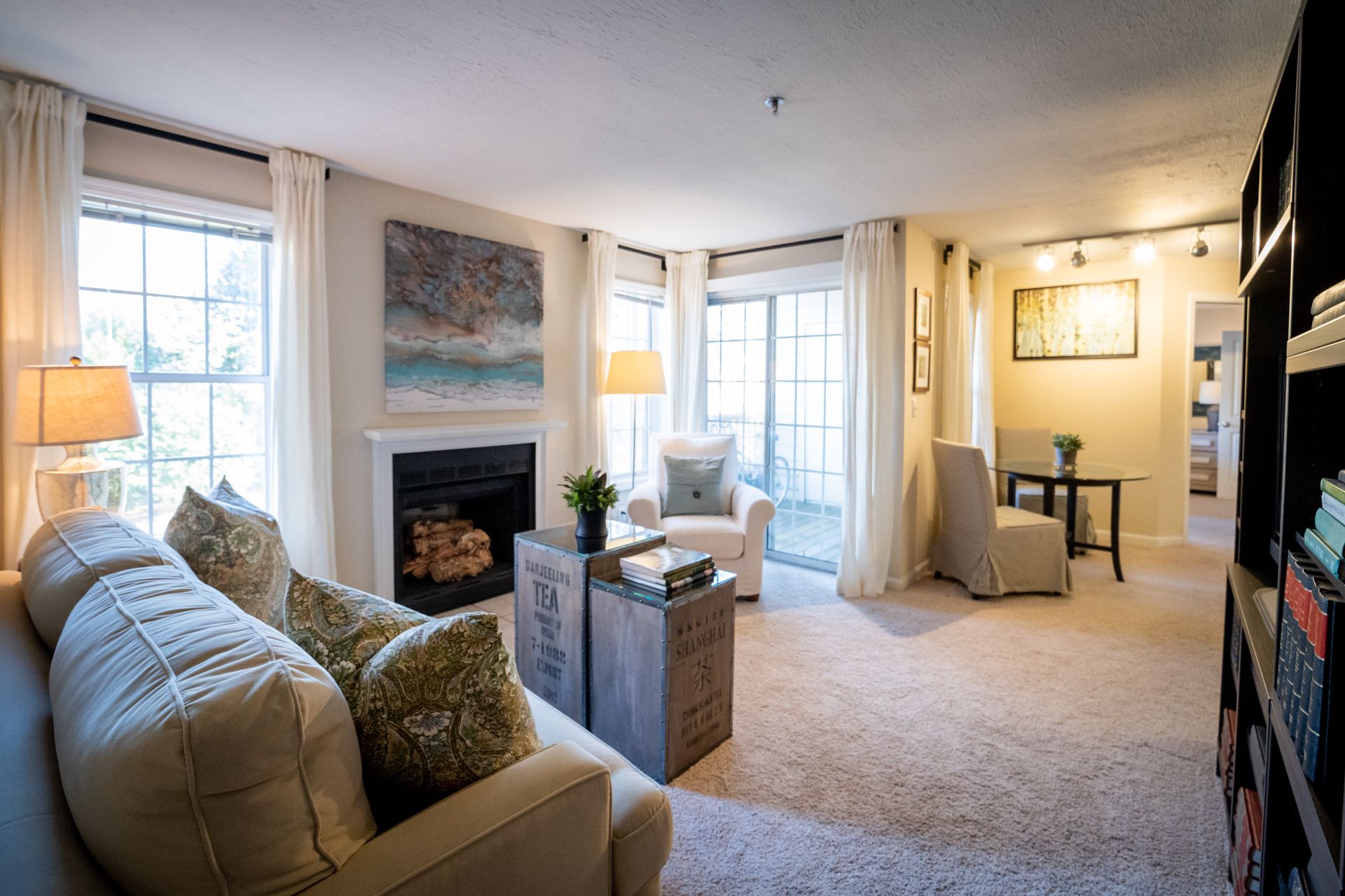 A living room with a couch , chair , fireplace and sliding glass doors.
