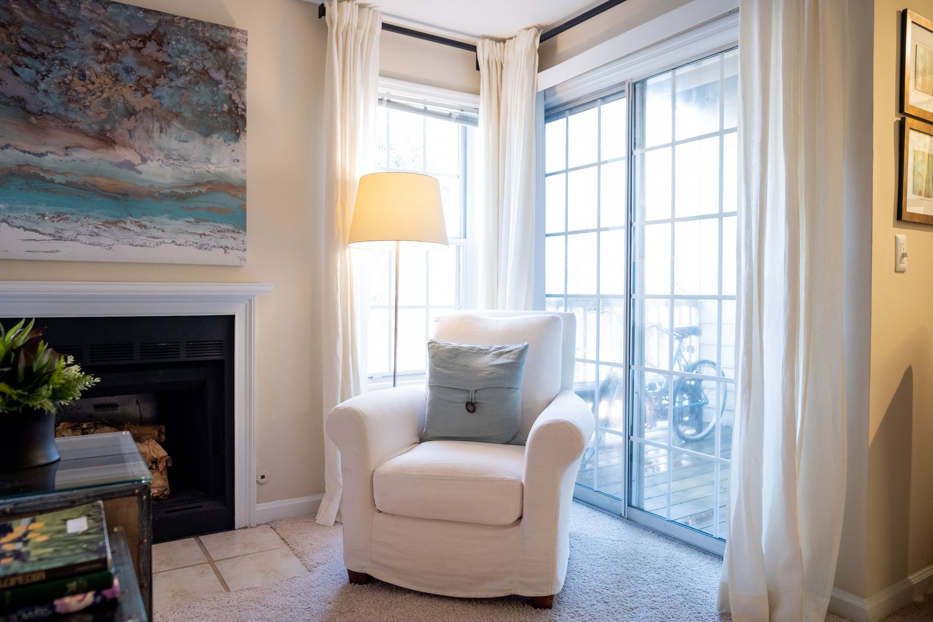 A living room with a chair , fireplace and sliding glass doors.