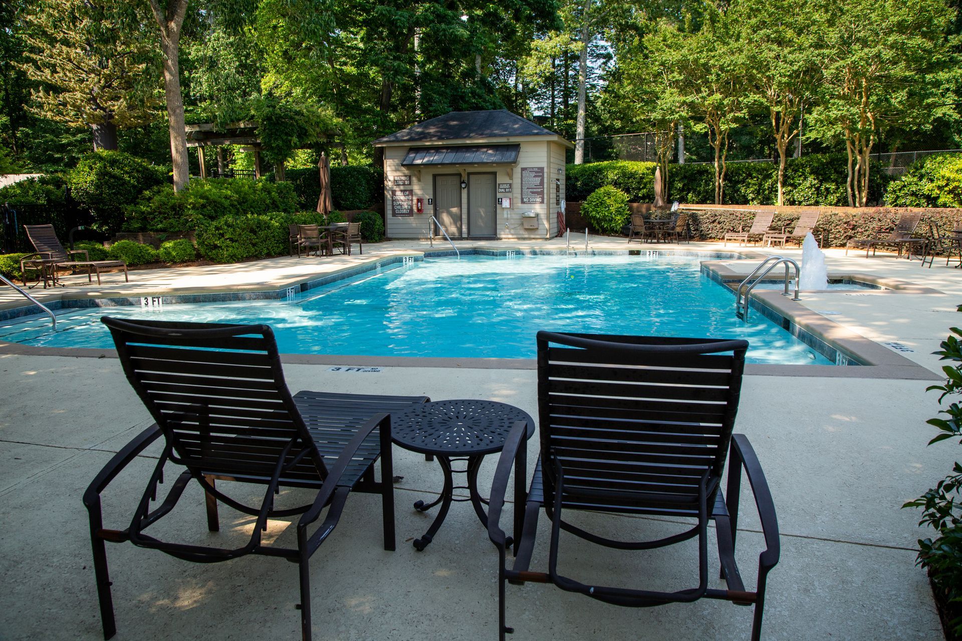 Two lounge chairs are sitting in front of a large swimming pool.