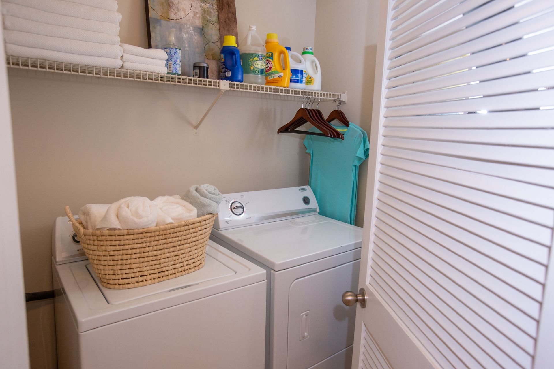 A laundry room with a washer and dryer and a basket of clothes.