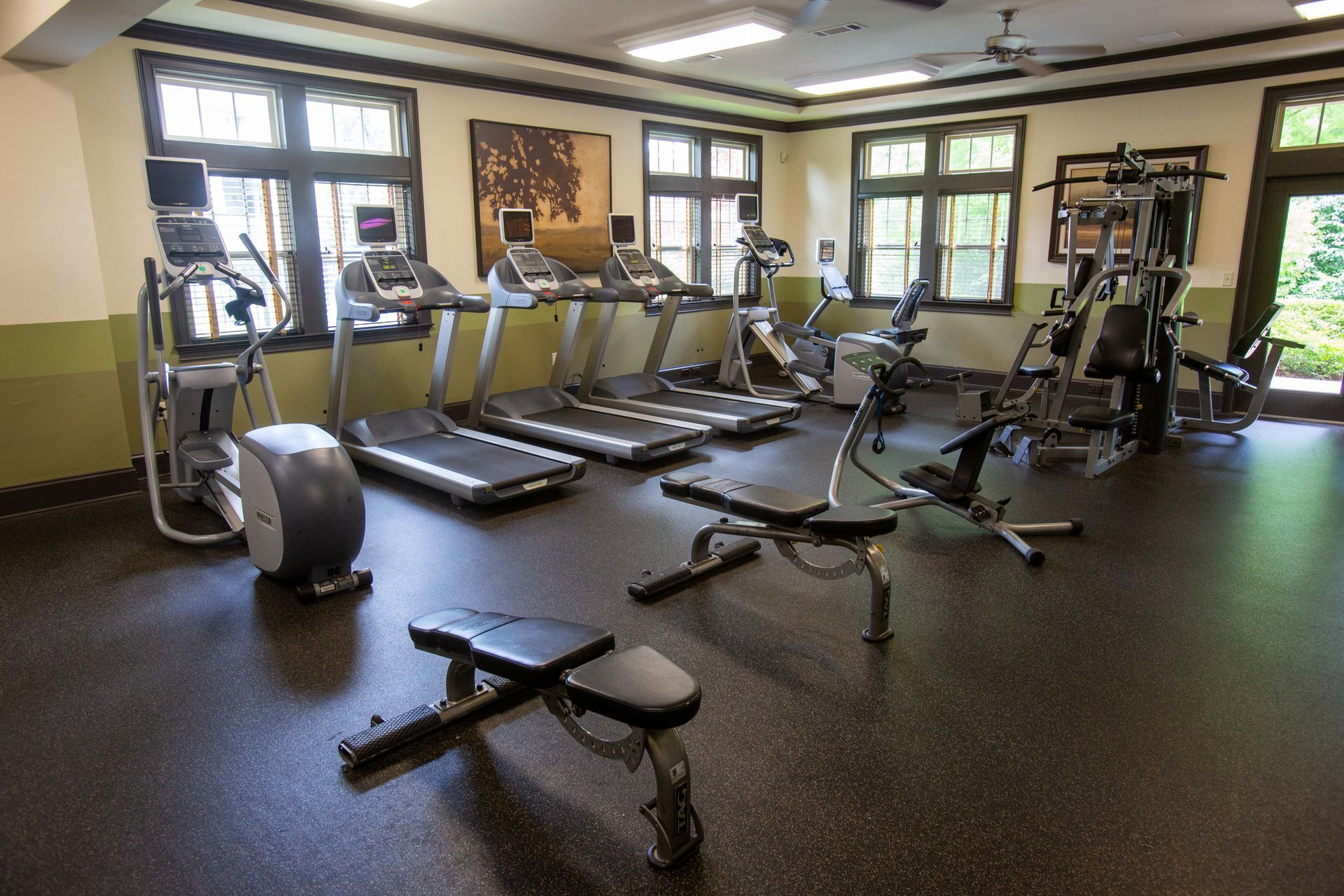 A gym with treadmills , exercise bikes and a bench