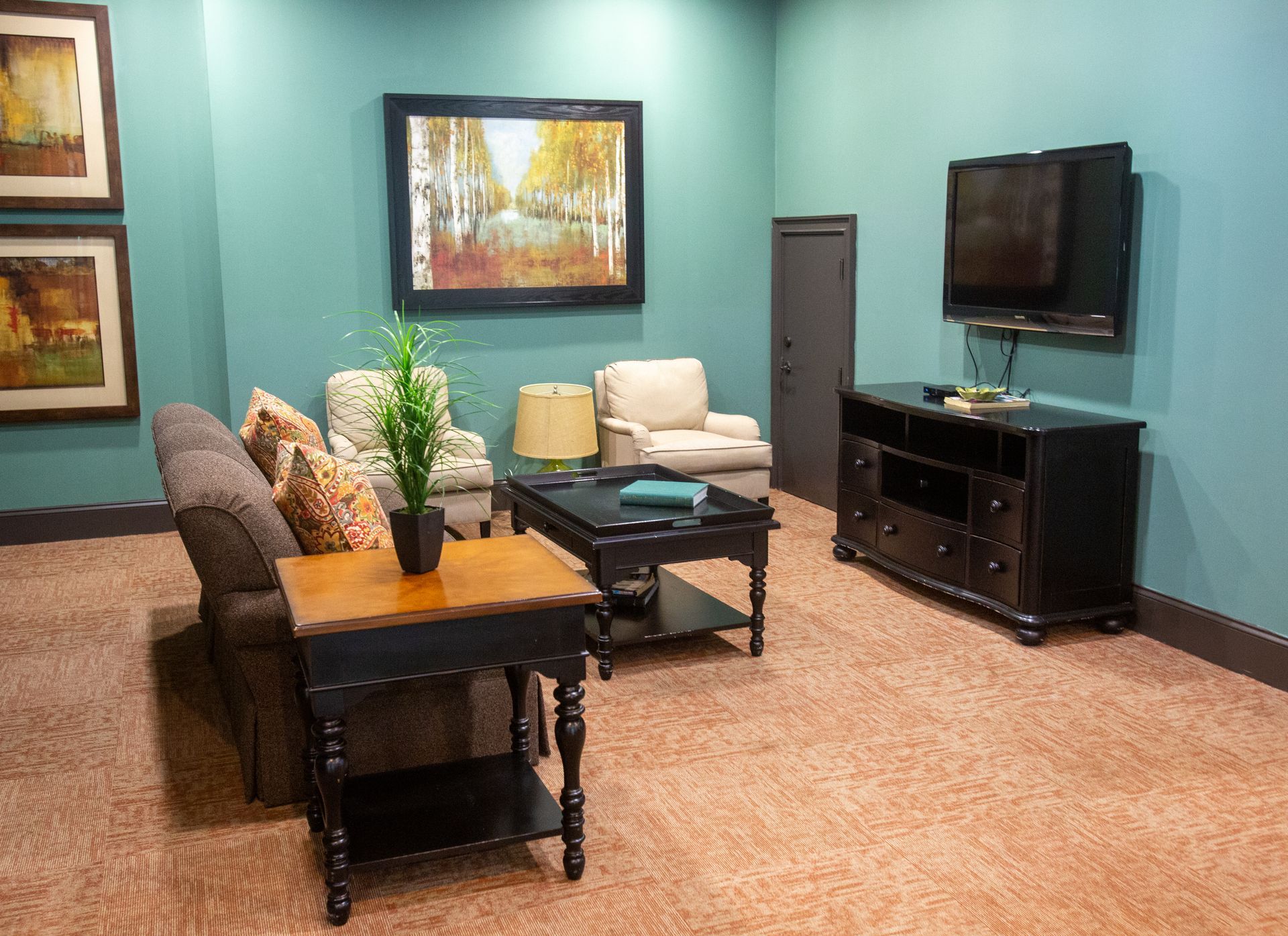 A living room with a couch , chairs , coffee table and television.