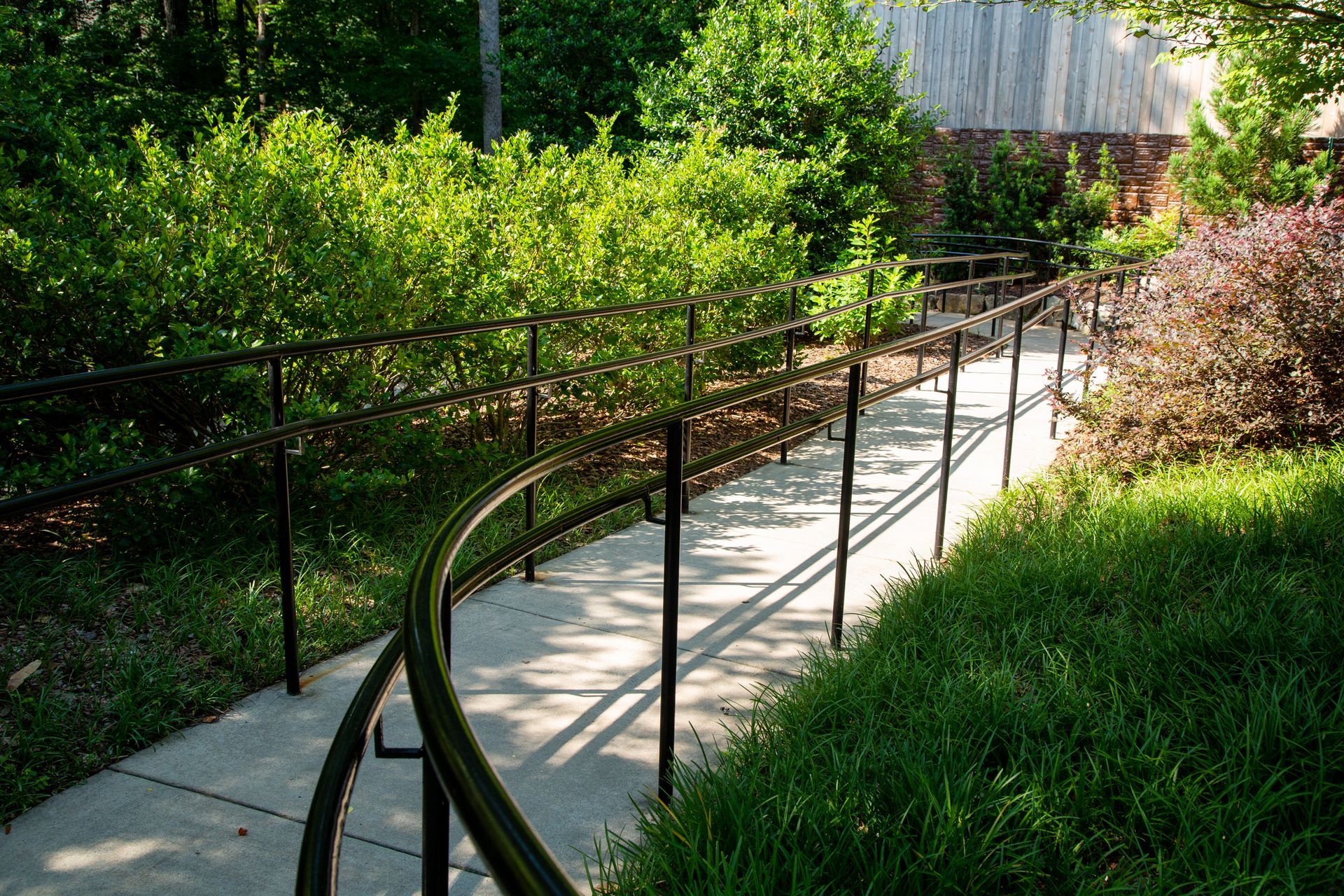 A concrete walkway with a metal railing in a park