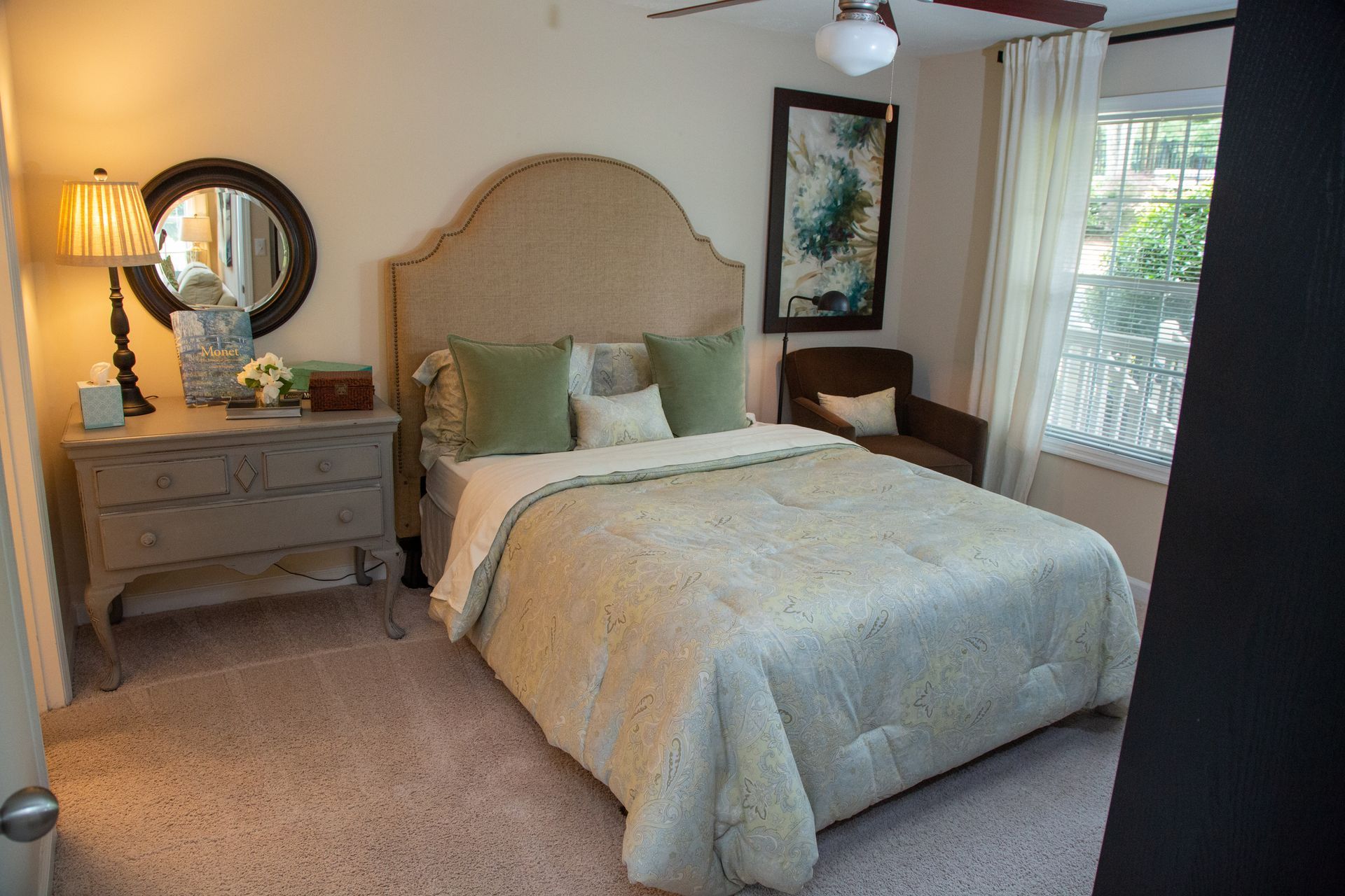 A bedroom with a bed , dresser , mirror and ceiling fan.