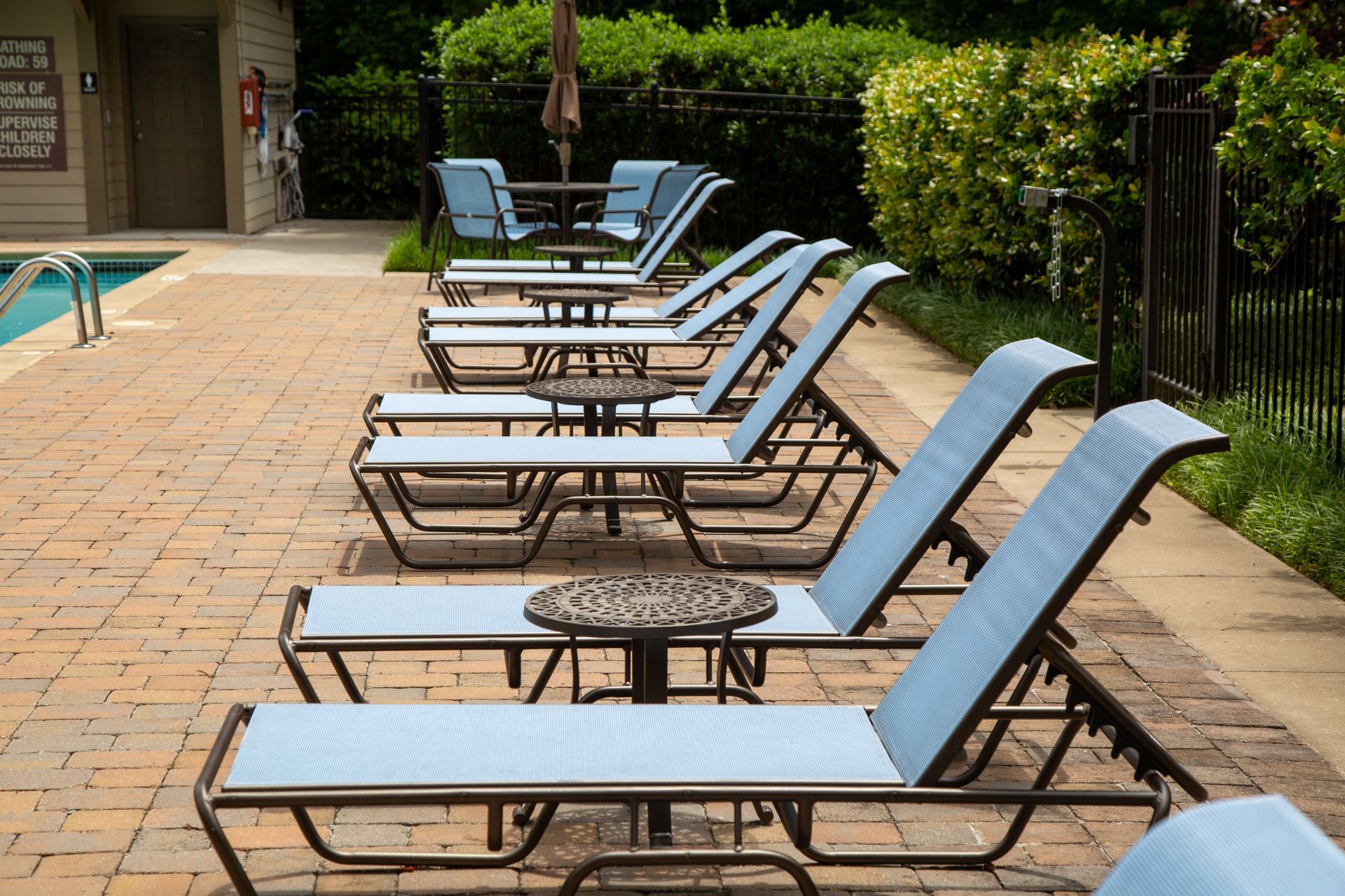 A row of lounge chairs are lined up next to a pool.