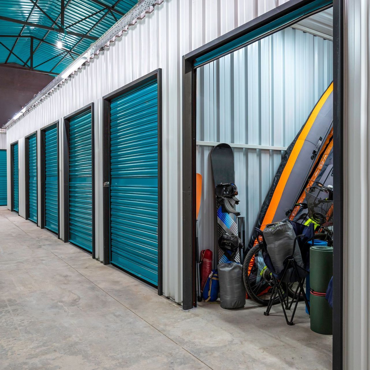 a row of storage units filled with bikes , snowboards , and kayaks .