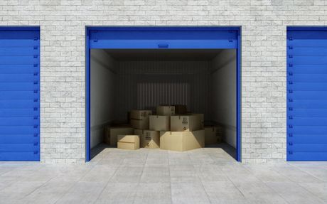 a stack of cardboard boxes in a garage with blue doors .