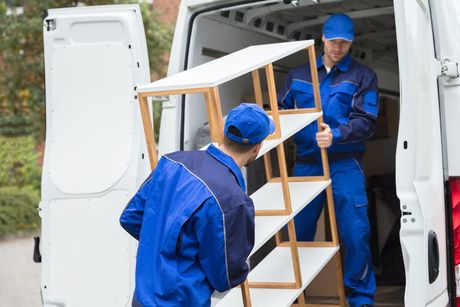 two men are loading shelves into a van .
