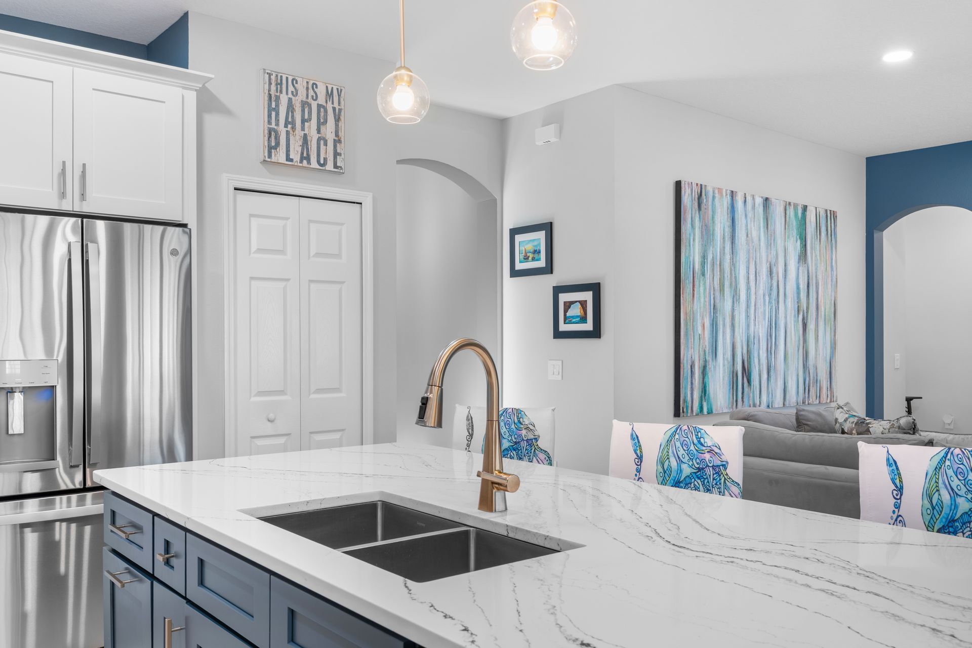 Modern kitchen with blue cabinetry, stainless steel appliances, and a white countertop.