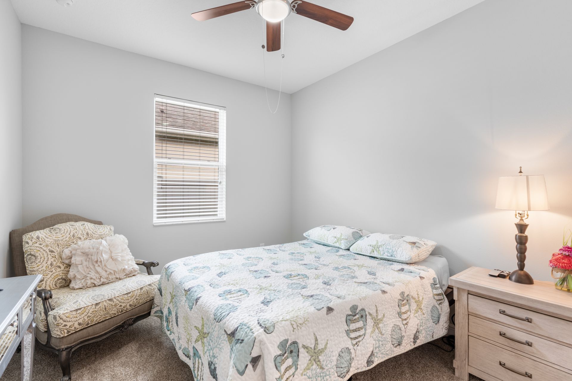 Bedroom with a double bed, armchair, window, nightstand, and ceiling fan.