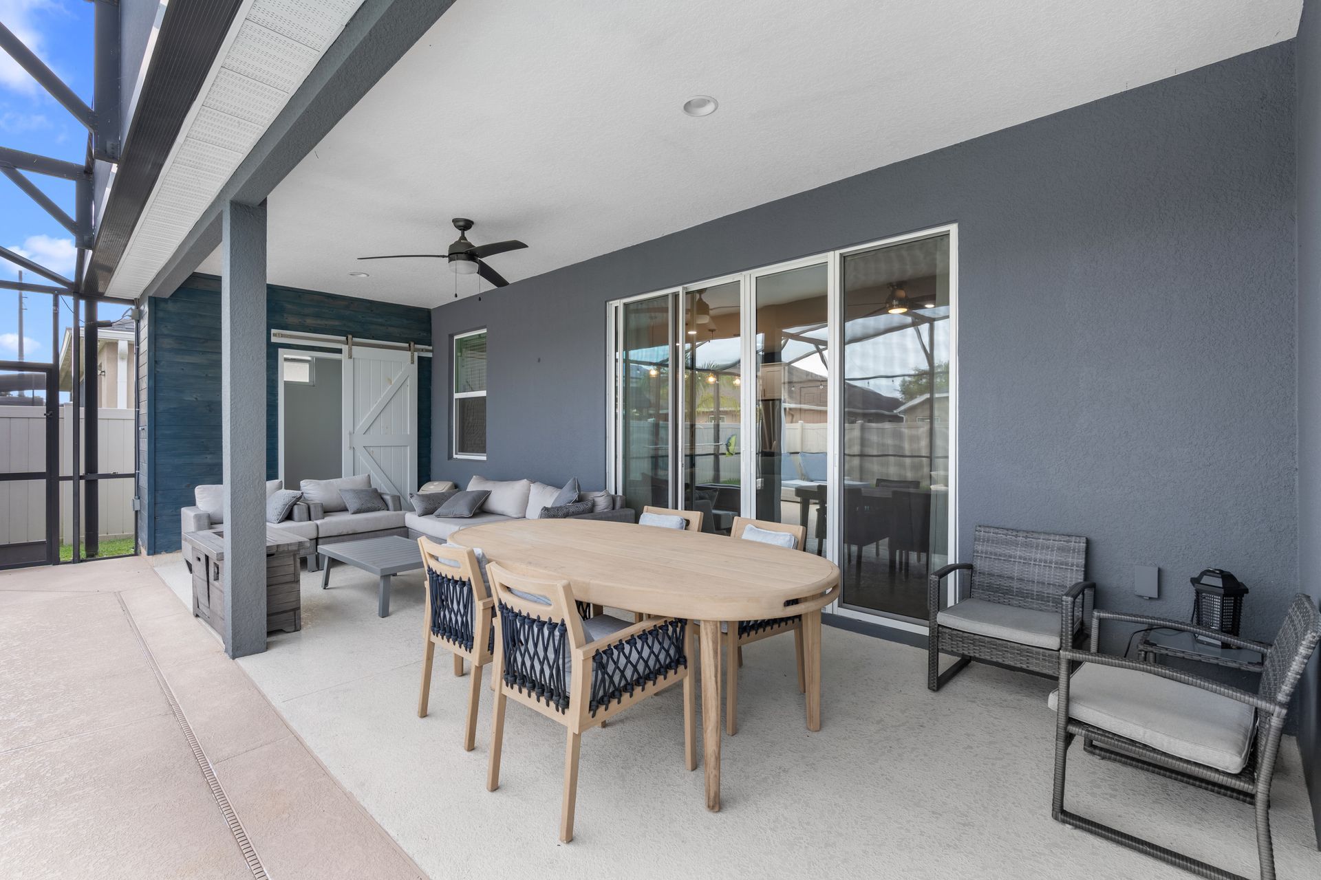 Patio with dining table, seating, and sliding glass doors against a gray wall.