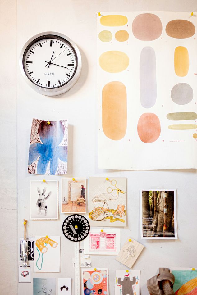 Wall with clock, art prints, and poster in various colors and shapes.