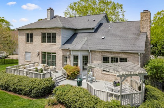 The back of a large brick house with a large deck.