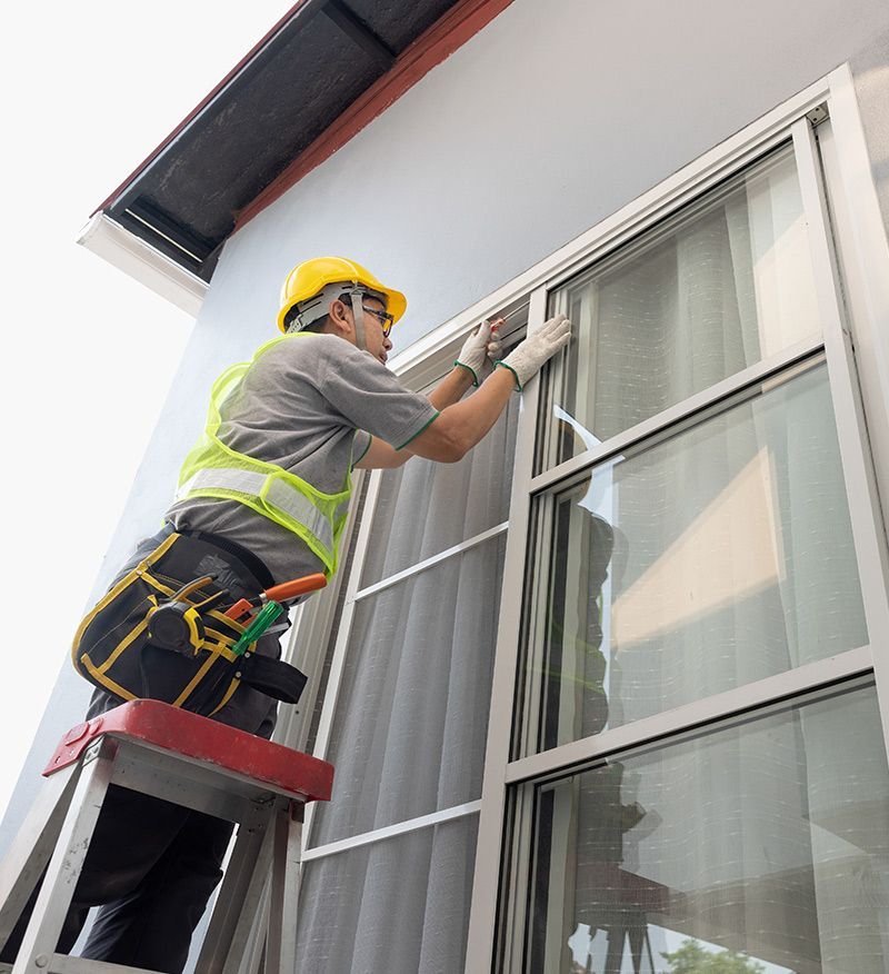 A man is standing on a ladder working on a window