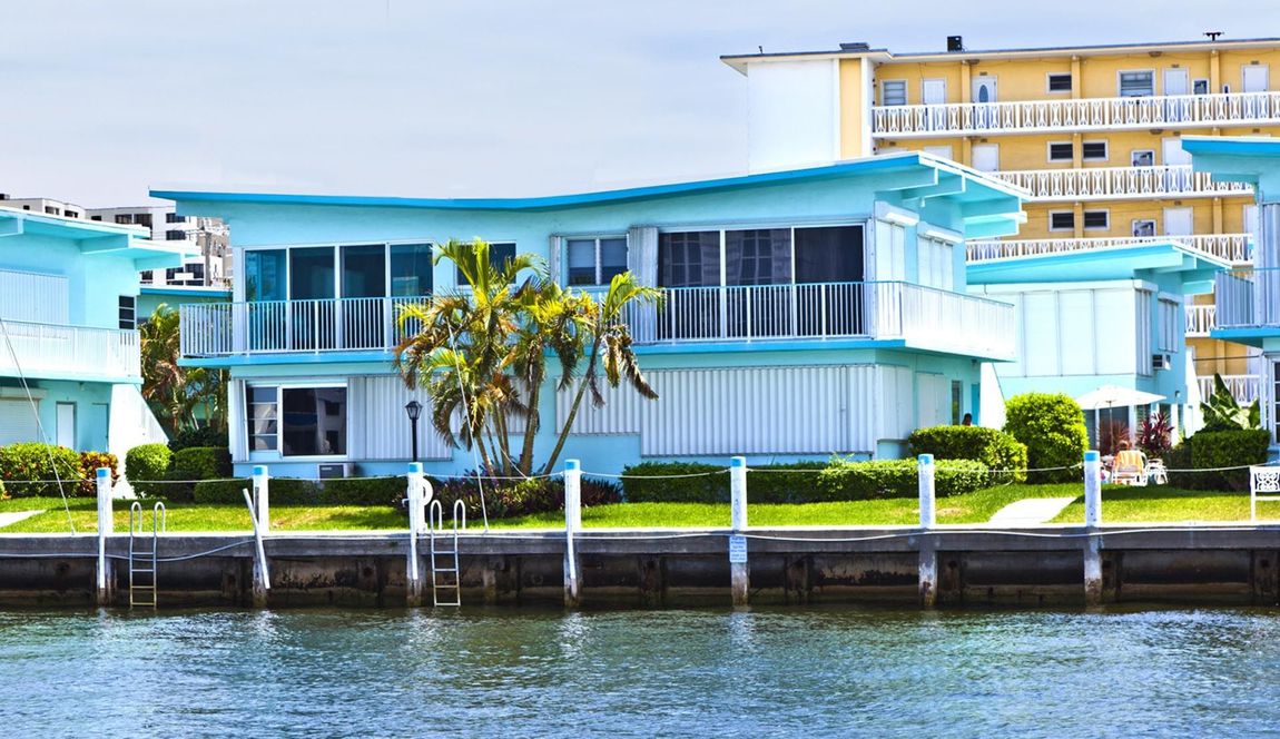 A blue and white house is next to a body of water.