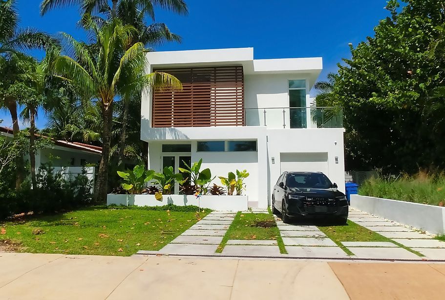 A white house with a black car parked in front of it