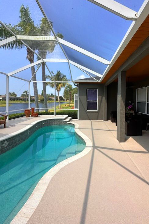 A large swimming pool is surrounded by a screened in area