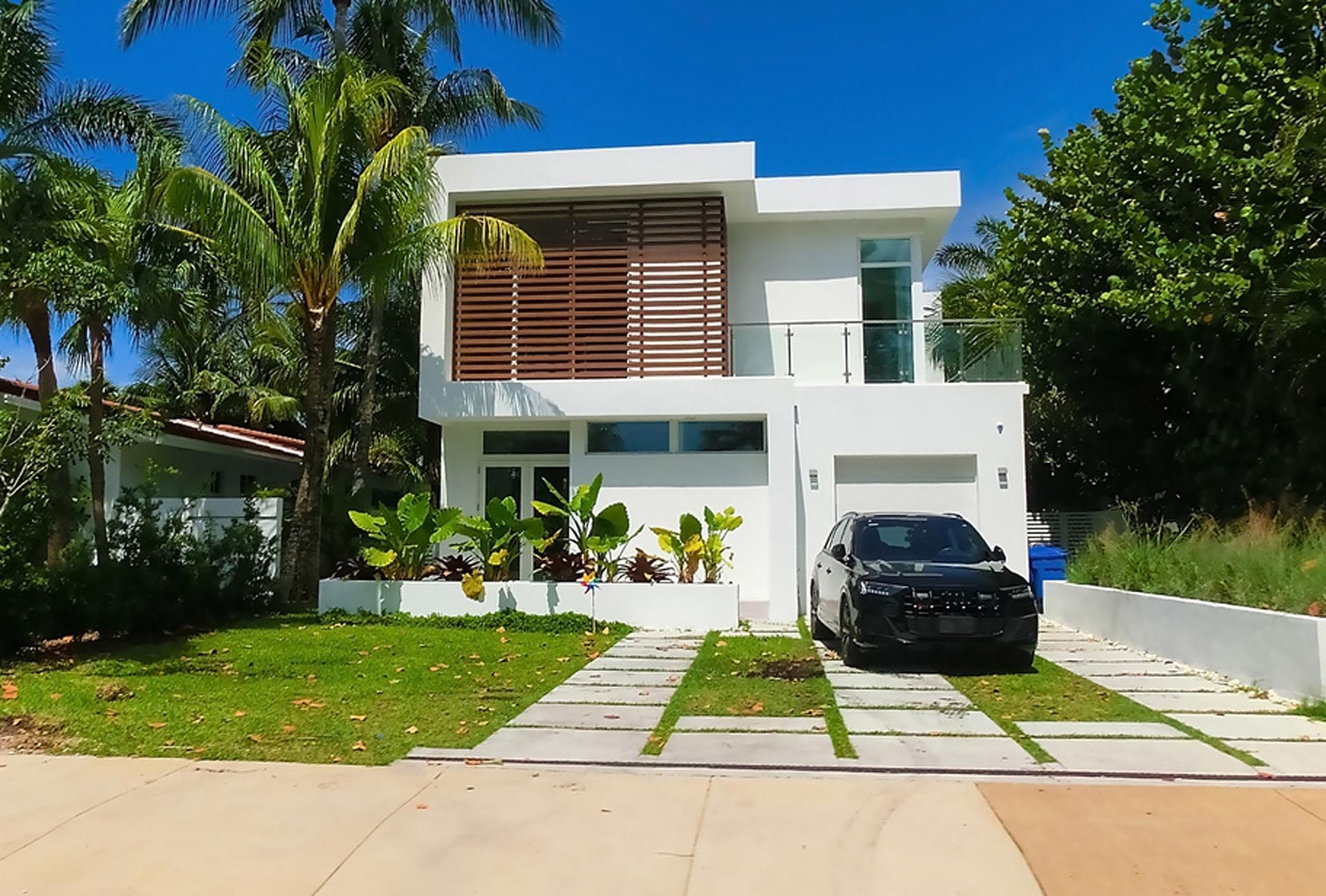 A white house with a black car parked in front of it