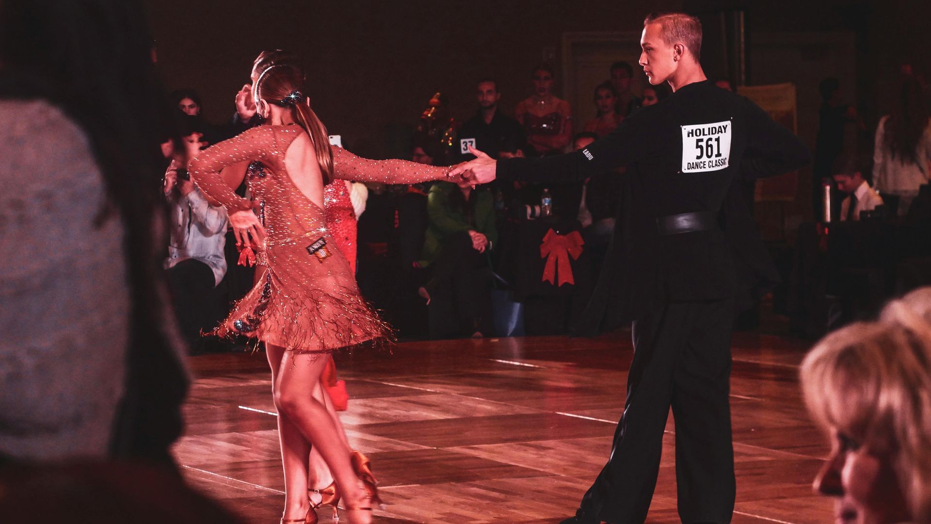 A man and a woman are dancing on a dance floor in front of a crowd.