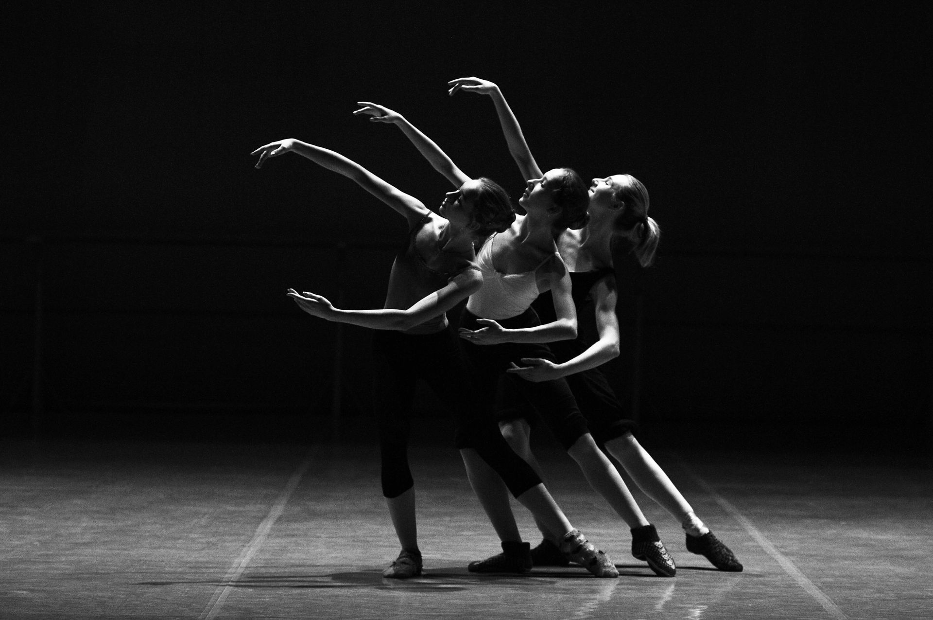 A group of dancers are dancing on a stage in a black and white photo.