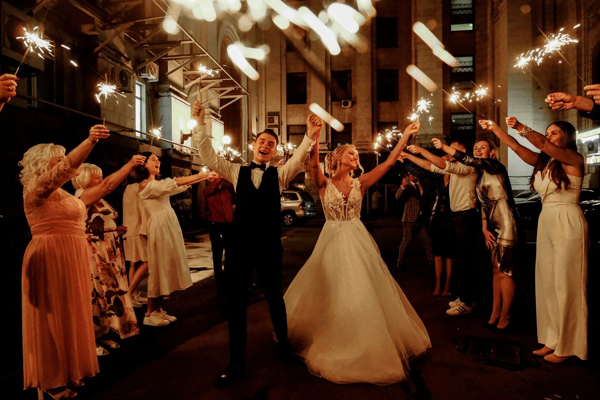 A bride and groom are walking through a tunnel of sparklers.