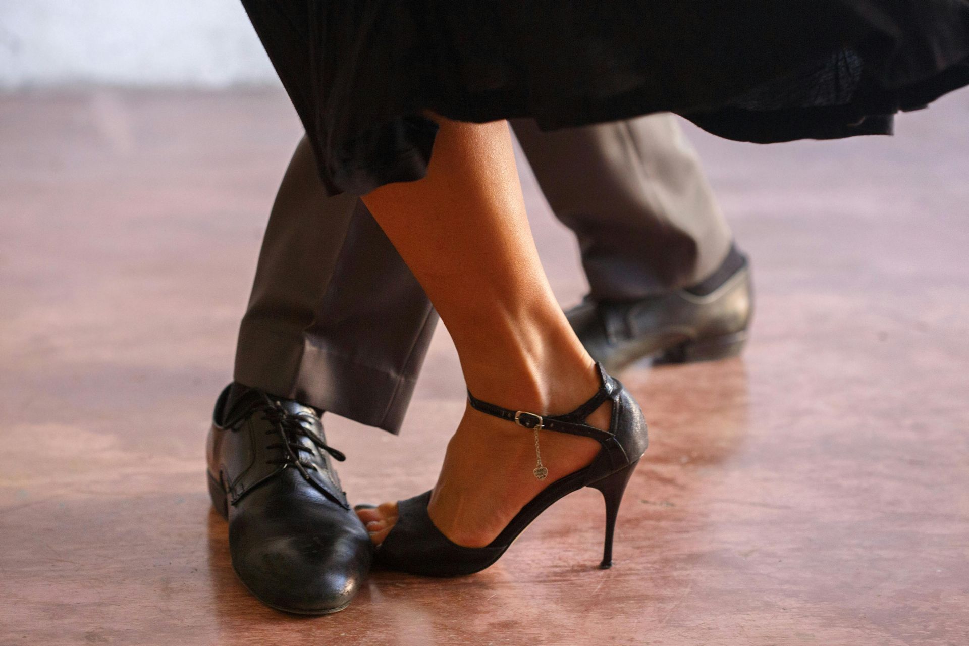 A man and a woman are dancing tango on a wooden floor.