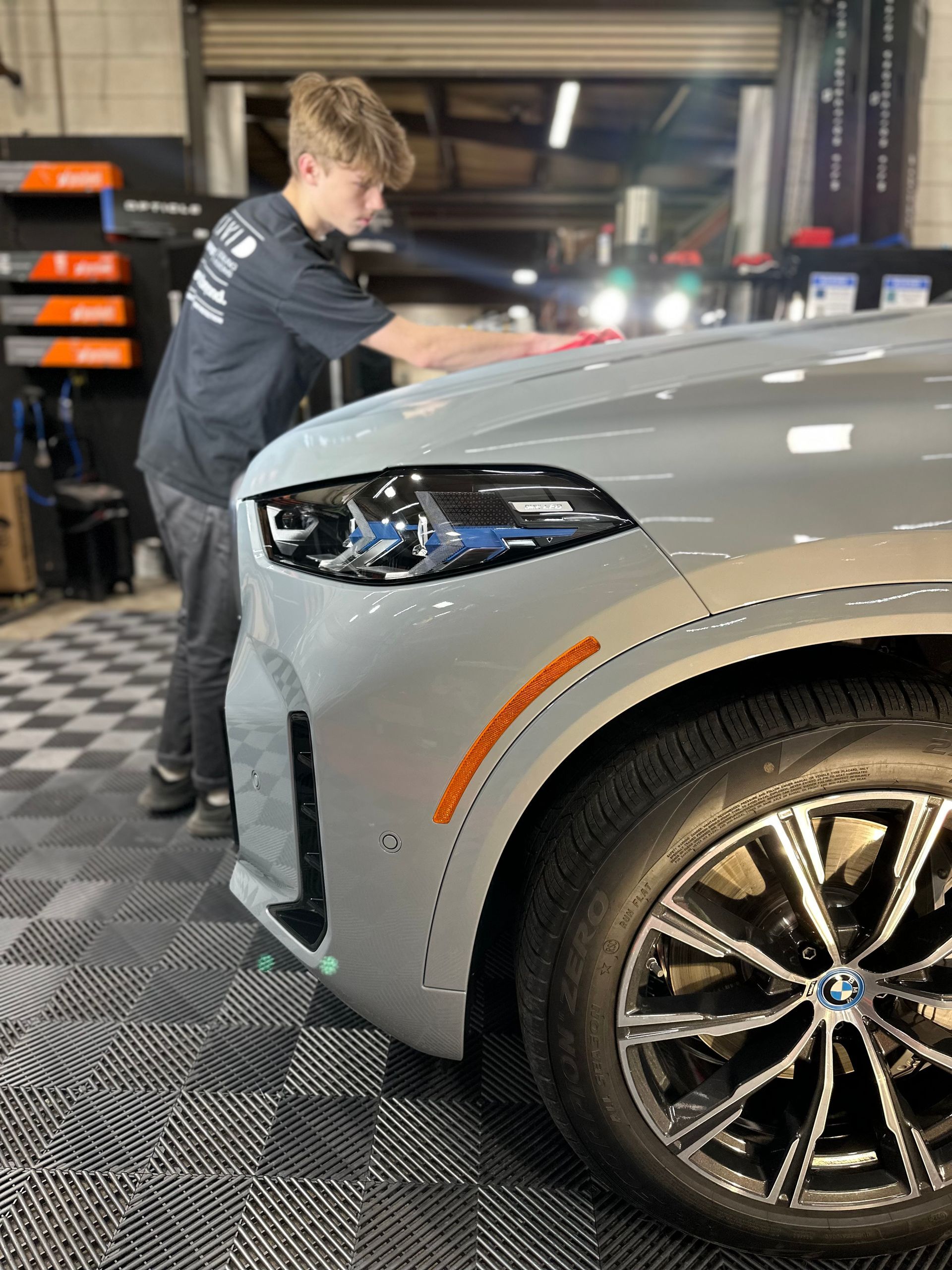 Young man detailing a gray BMW car in a garage.