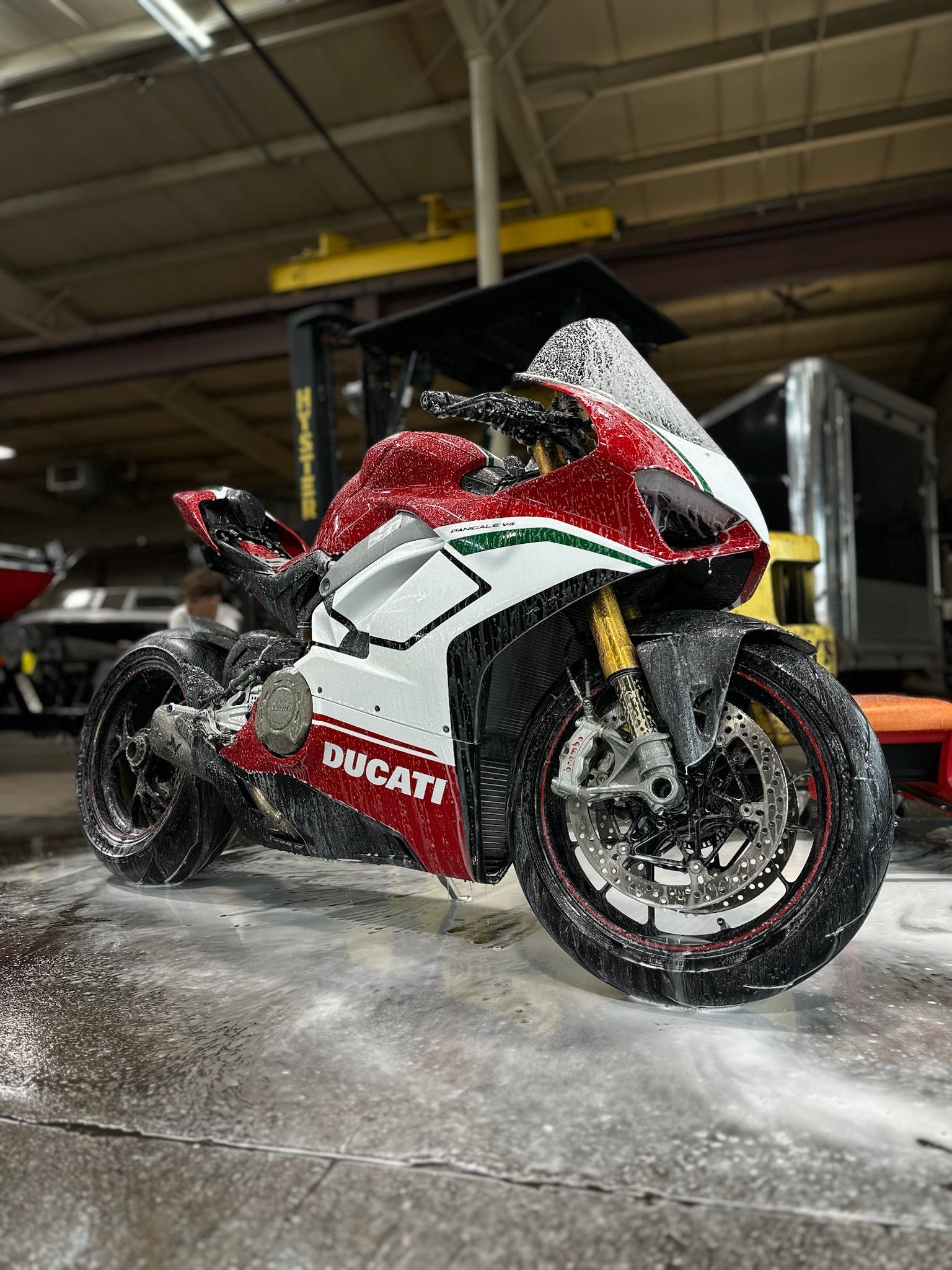 Red, white, and green Ducati motorcycle covered in soap in a garage.