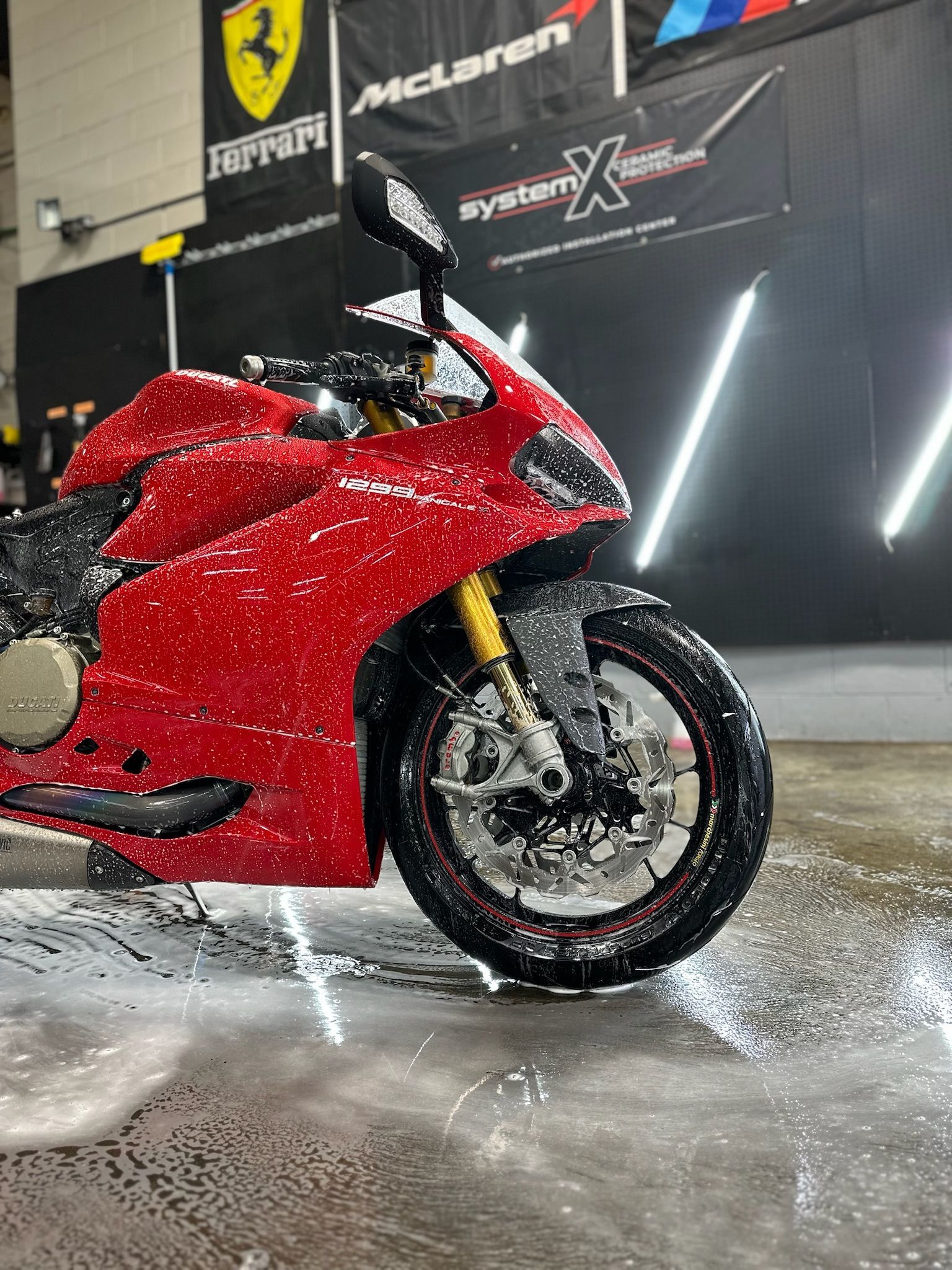 Red motorcycle covered in suds, being washed in a garage.