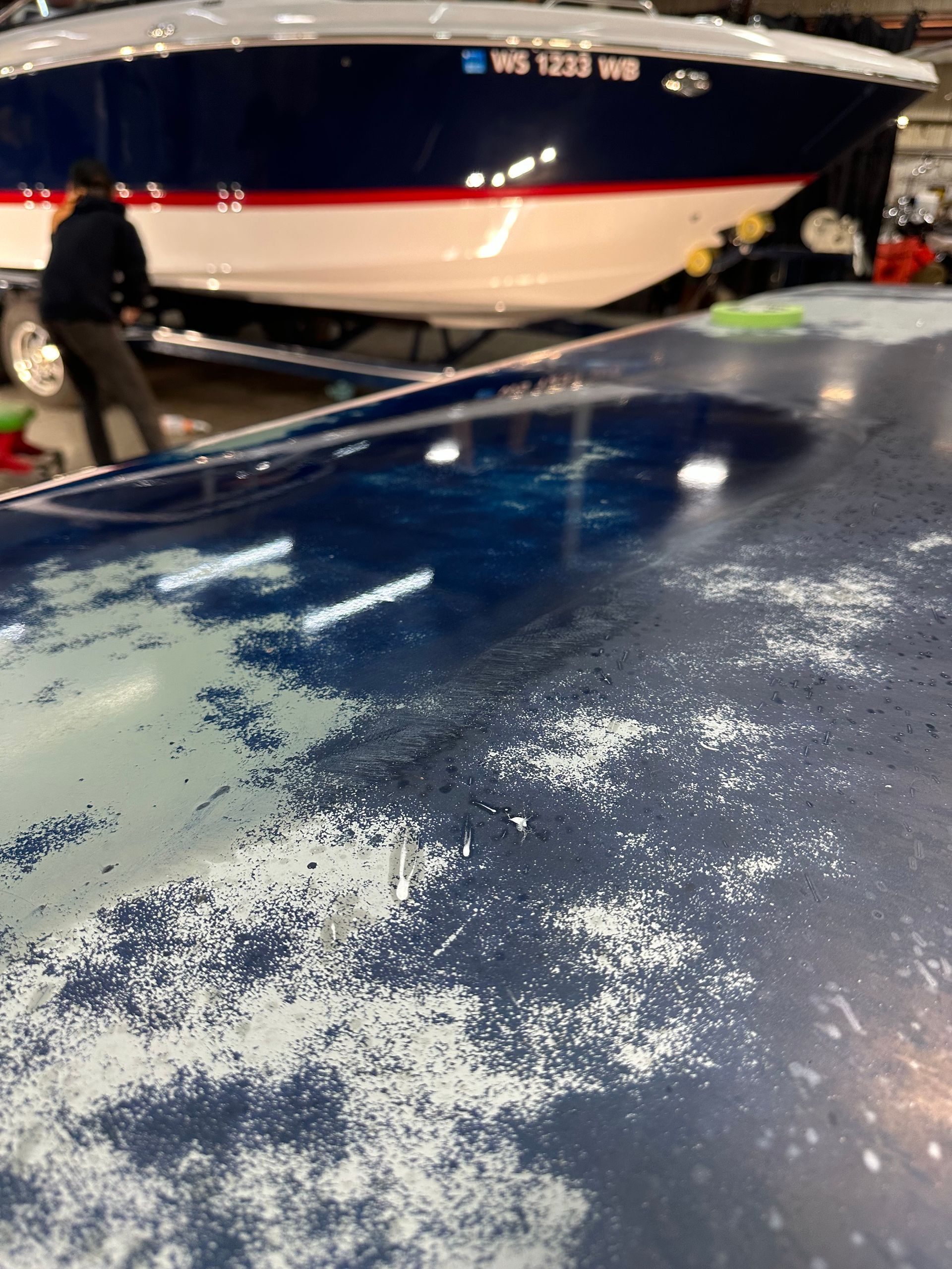 Close-up of peeling blue paint on a car roof with a blue and white boat in the background.