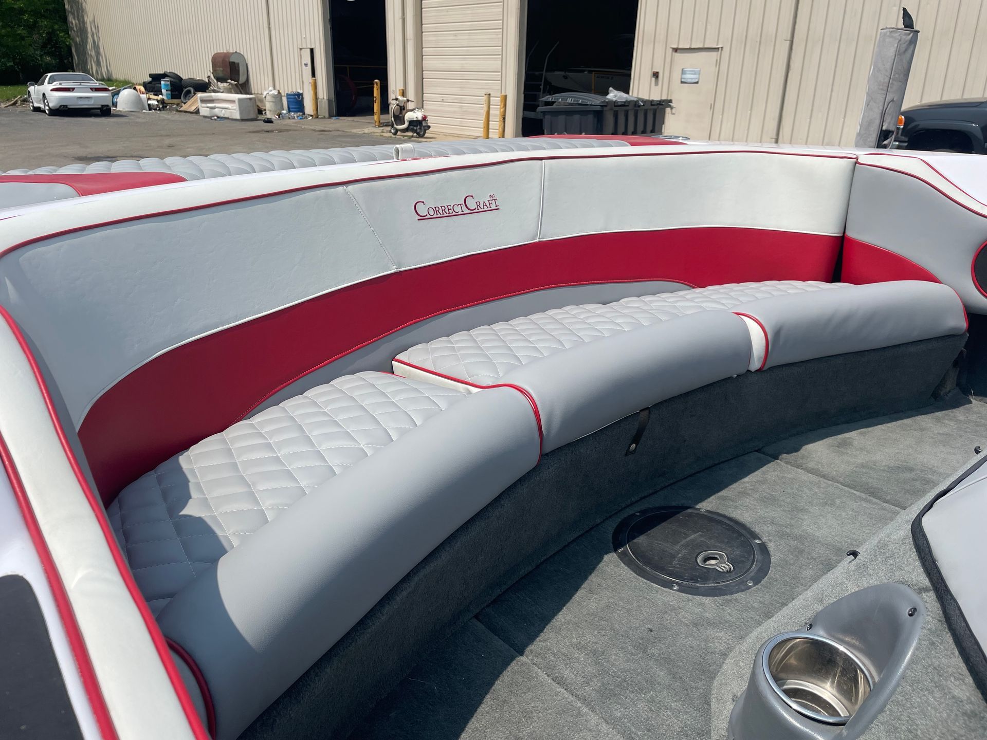 Gray and red boat seating. Close-up view of curved boat seats with quilted gray cushions and red trim.