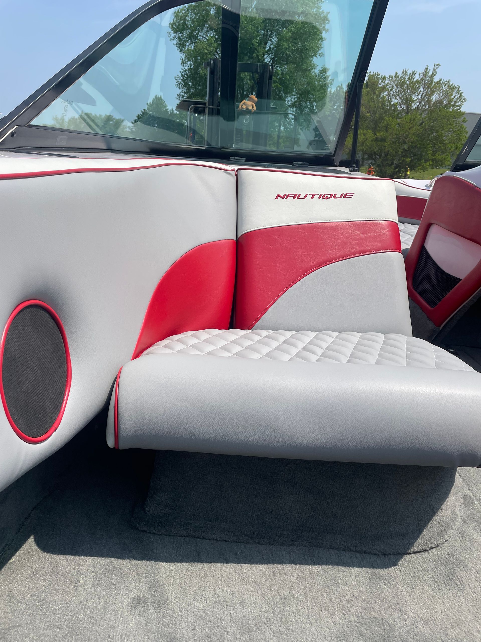 Boat interior with gray and red upholstery, a speaker, and a windshield.