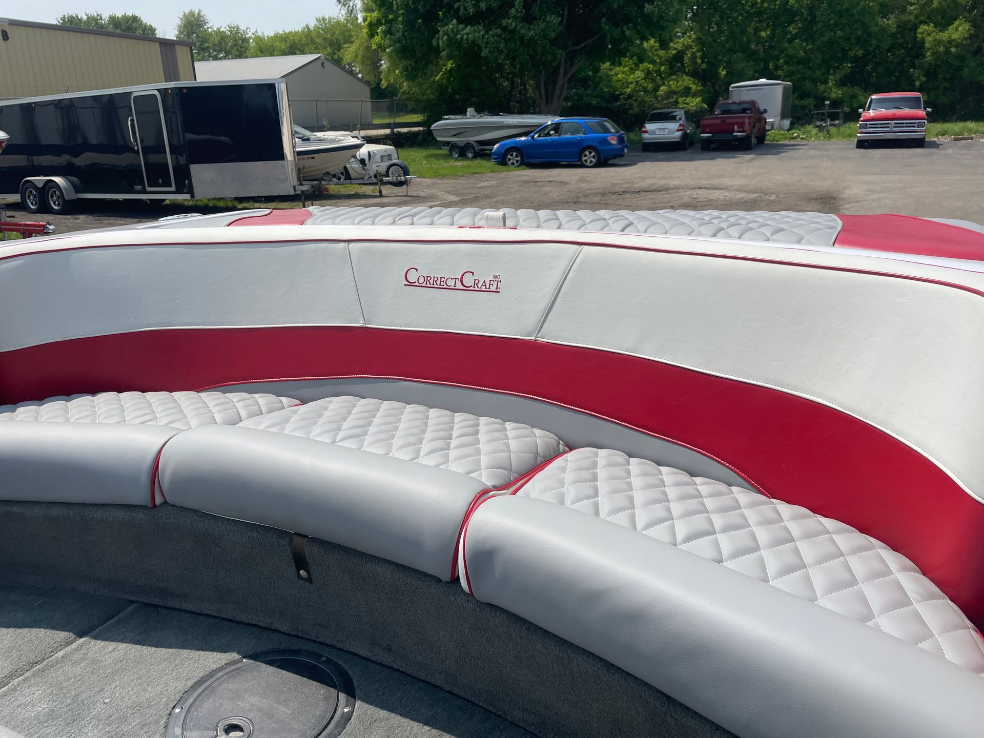 Boat seating, gray diamond-stitched cushions with red trim.