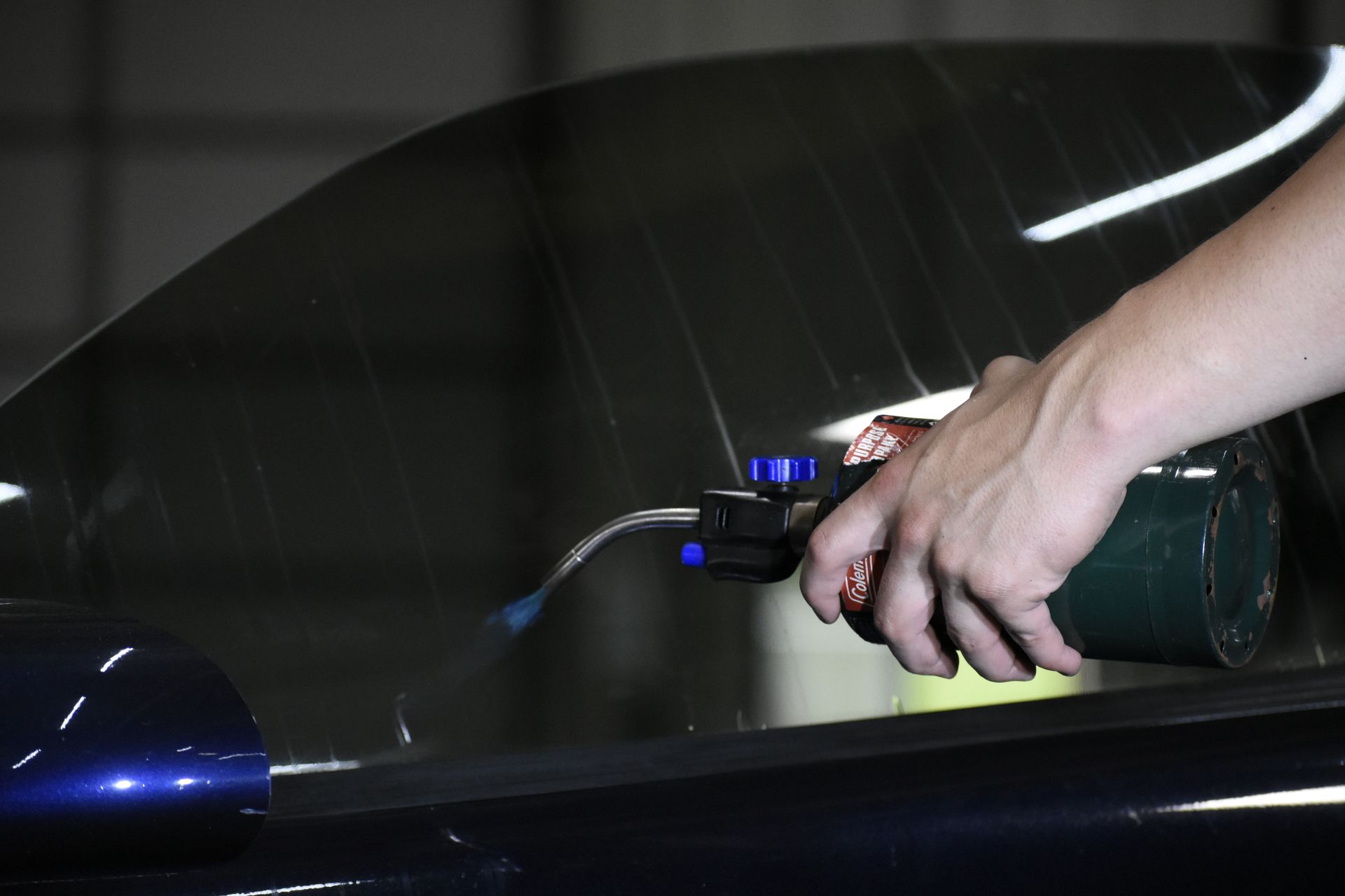 Person using a torch to apply tint film to a car window.